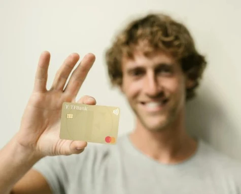 Uomo sorridente con  una TF Mastercard Gold in mano