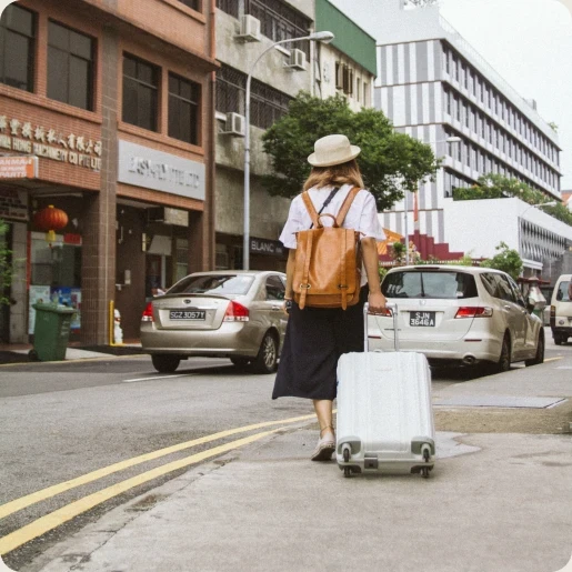 mochilera empujando una maleta en una calle