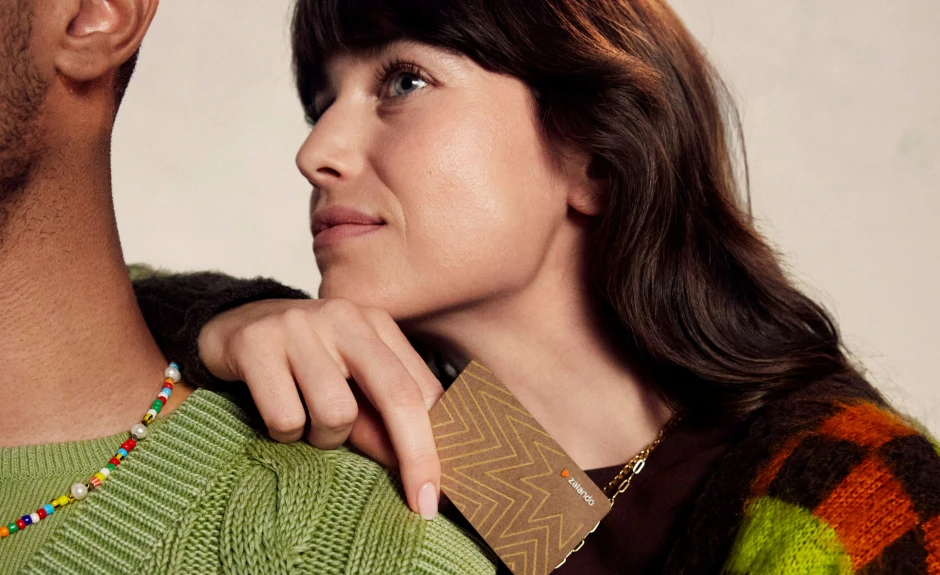 Donna e uomo con abiti zalando che tengono in mano una E-card zalando